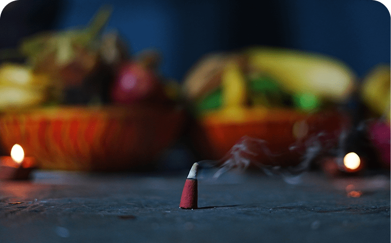 Burning incense cone with fruits in background